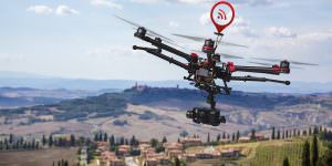 A flying helicopter with raised landing gears and a camera with blured hills of Tuscany in the background